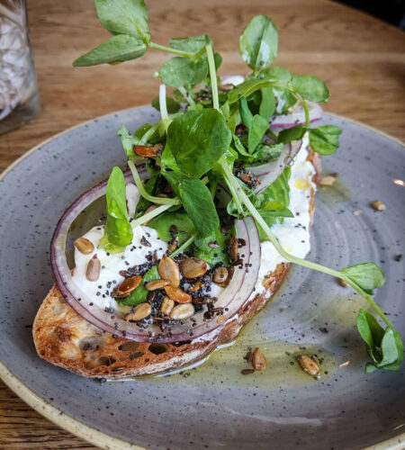 A breakfast toast, topped with ricotta and pea shoots.