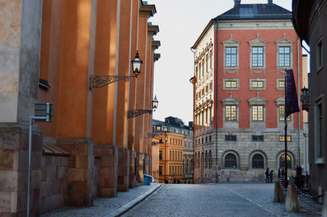 Cobbled streets on Gamla Stan, with orange and salmon-coloured buildings flanking either side of the pavement.