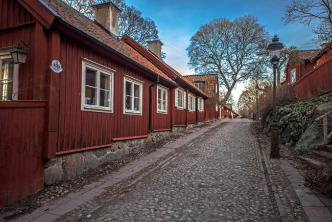 Lotsgatan in Södermalm. A cobbled street lined with traditional falu-röd (a dark red) wooden houses.