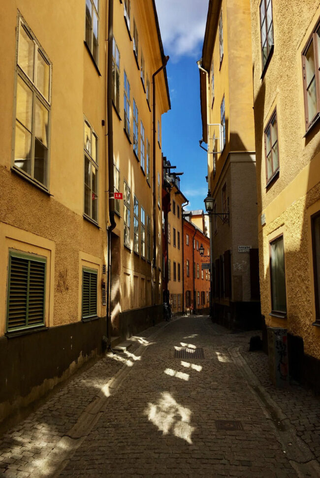 Cobbled streets on Prästgatan. Yellow and orange buildings stand either side. 